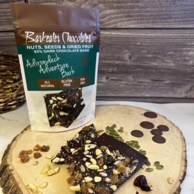 Loose dark chocolate with nuts, seeds, fruit and pouch on wood slab