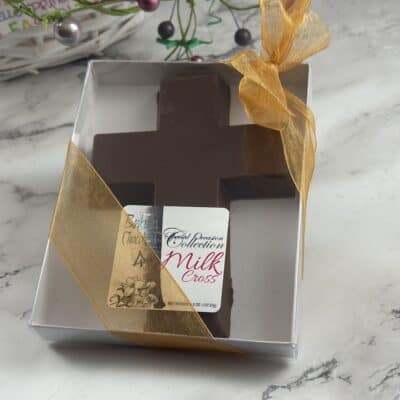 solid milk chocolate cross inside box with clear lid on table