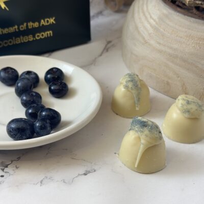 loose white chocolate truffles next to a plate of blueberries