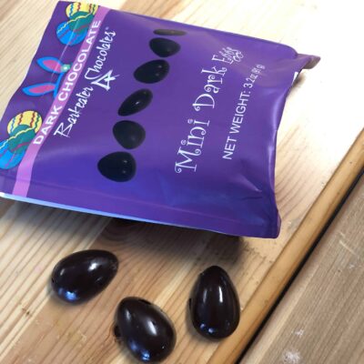 Purple pouch containing small dark chocolate eggs