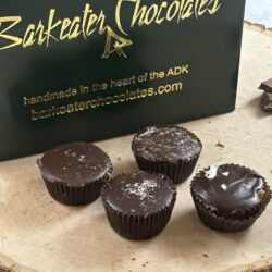 dark chocolate caramels loose on wood with box behind them