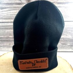 Black knit cap with leather patch on front that has Barkeater Chocolates logo and North Creek NY