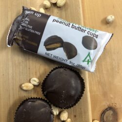 loose and packaged dark chocolate peanut butter cups with peanuts on a table